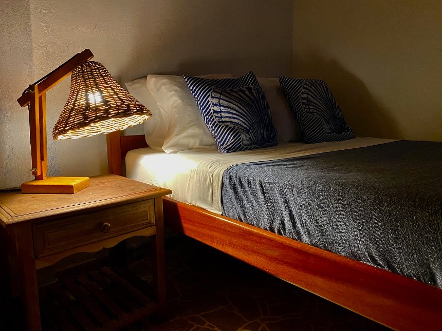 Cama e criado-mudo de madeira maciça com luminária artesanal