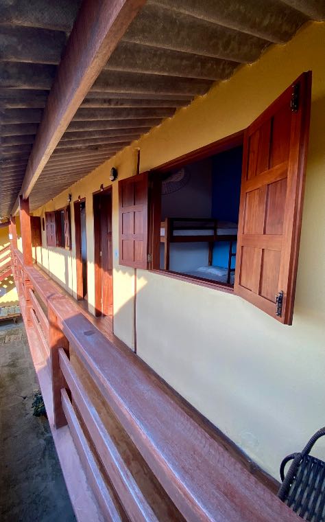 Corredor externo com janelas e venezianas de madeira